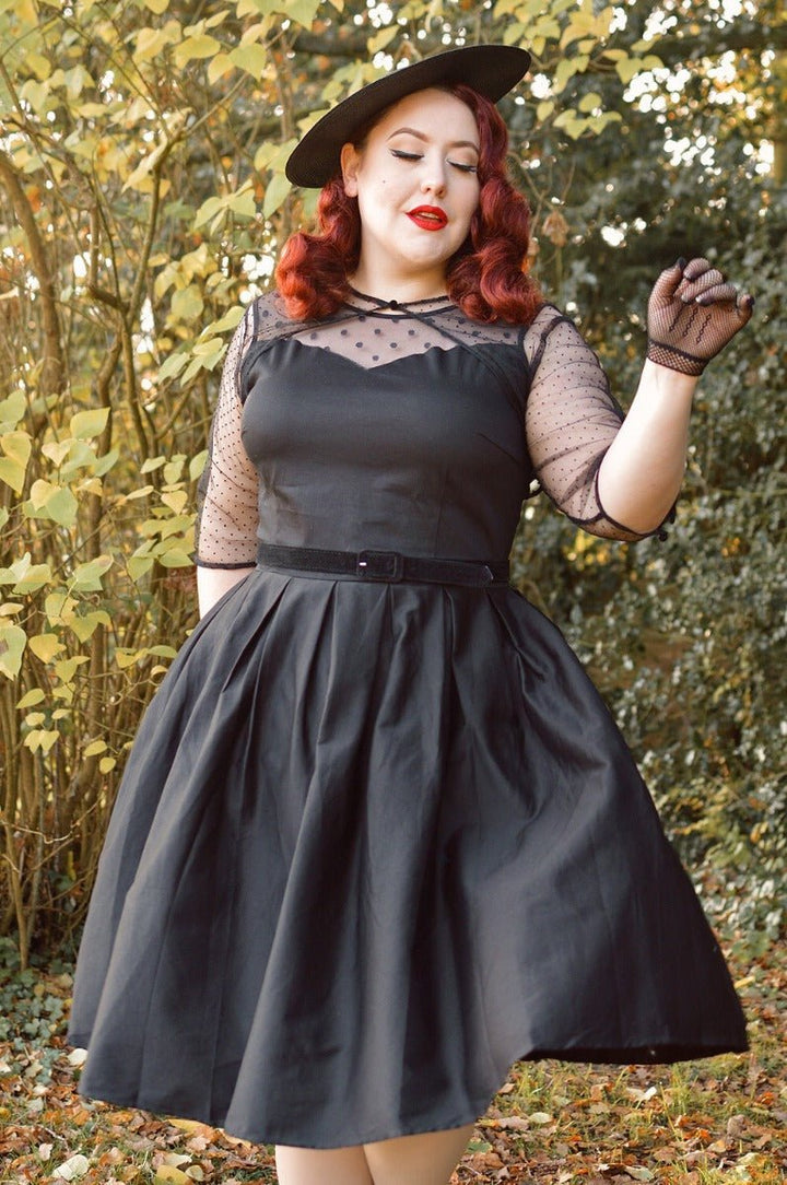 Model posing in an Elizabeth Black Occasion Dress featuring a delicate mesh neckline.