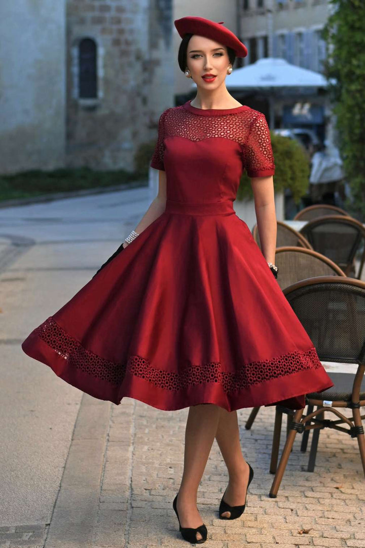 A mode wearing a Tess Crochet Lace Formal Dress In Burgundy in a outdoor cafe